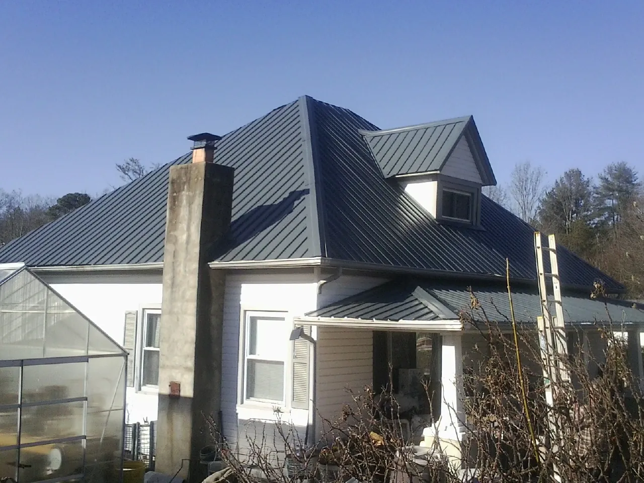 Dark blue standing seam metal roof on a white farmhouse with dormer — Slate & Tile Roof Repair by Roofing Brothers in West Sacramento