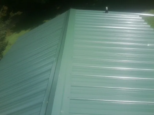 New green metal panels meeting at the ridge of a roof — Flat Roof Repair work by our crew in West Sacramento