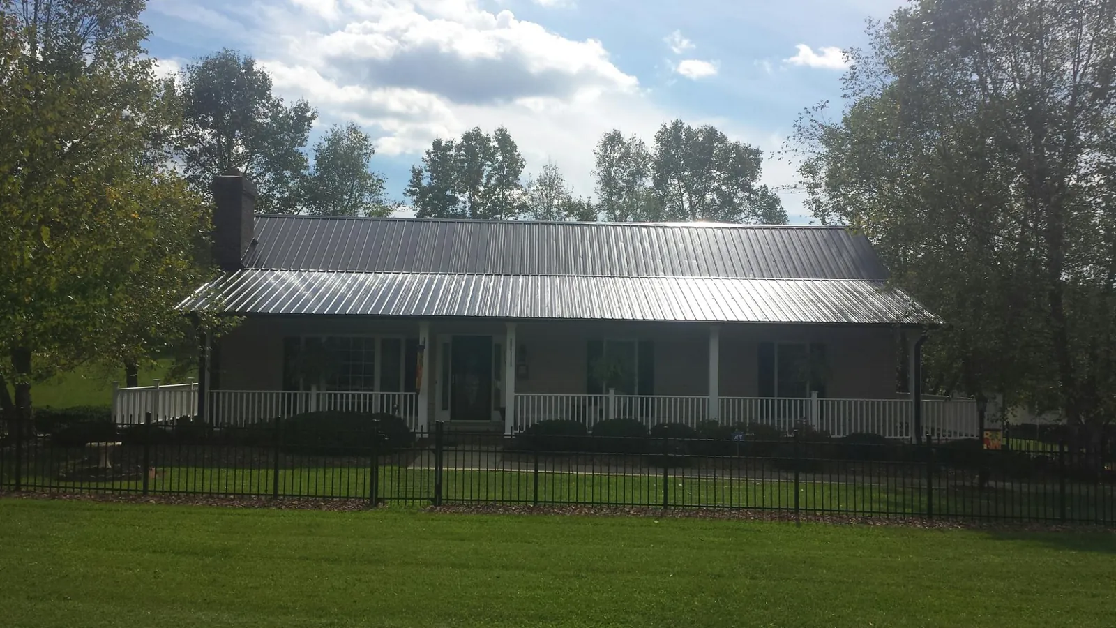 Gray metal roof on a brick ranch with a full width front porch — Gutter Guard Installation work by our crew in West Sacramento