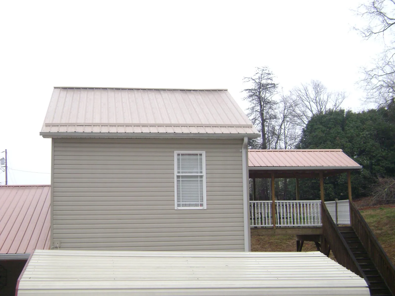 Tan metal roofs on a two story addition and attached porch, from a Roof Replacement job in West Sacramento