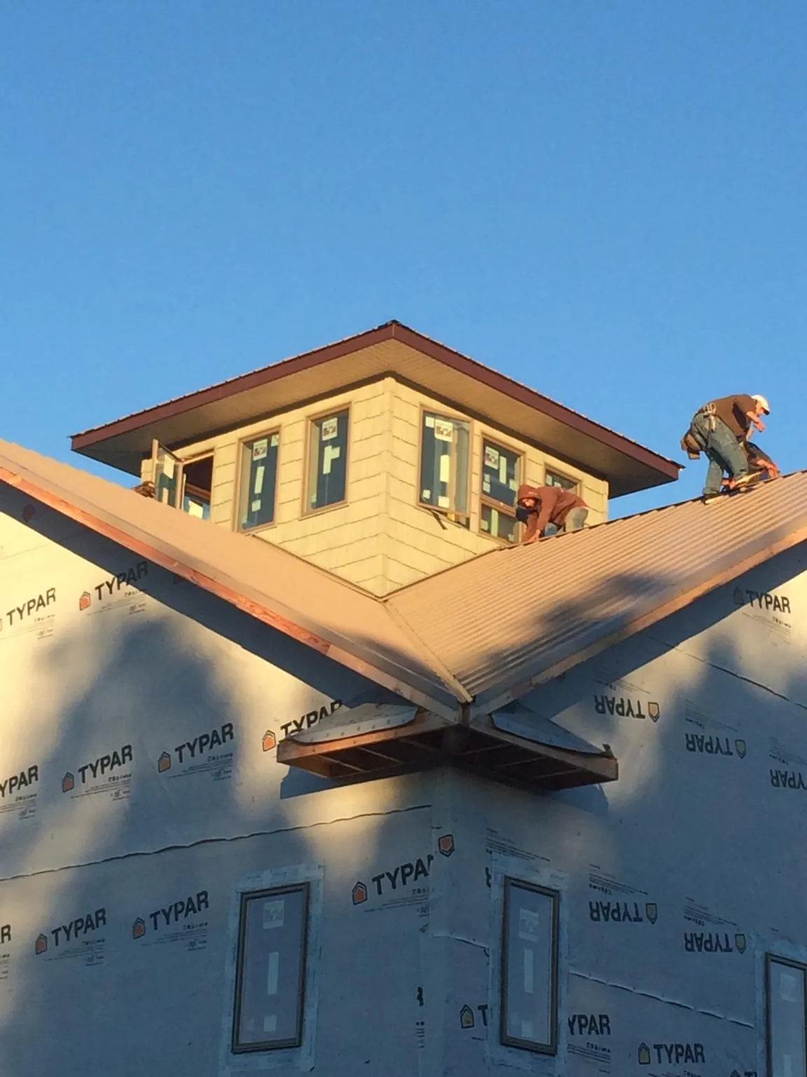 Roofers working around a rooftop cupola on a new metal roof at sunset — Roof Waterproofing in West Sacramento by Roofing Brothers